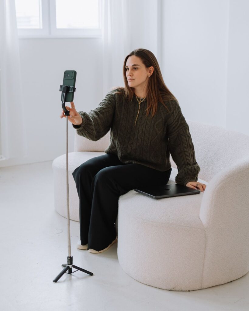 Janique sitzt mit Smartphone auf einem Sofa und nimmt ein Video auf.